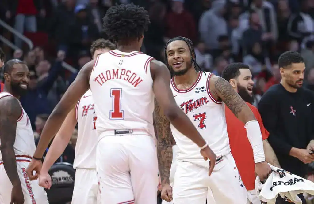 Houston Rockets players smile and celebrate together on the court after a play.