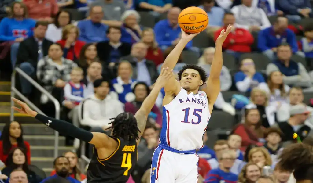 Kansas Jayhawks player takes a jump shot over TCU Horned Frogs defender during NCAA basketball game.