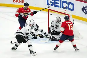 Florida Panthers player attempts a shot on goal as Los Angeles Kings goalie and defenders block.