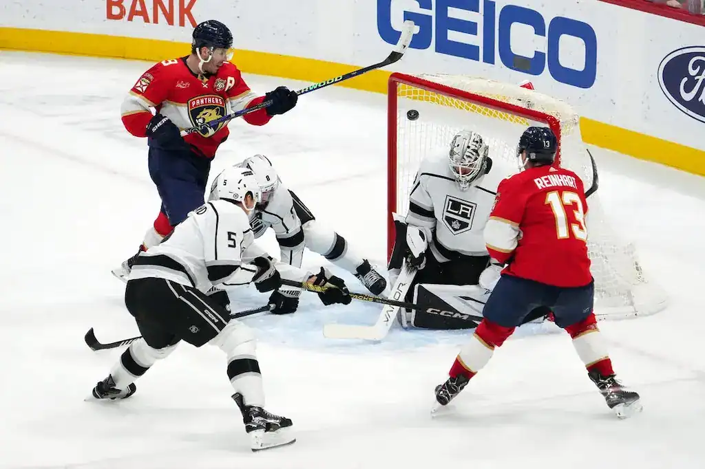 Florida Panthers player attempts a shot on goal as Los Angeles Kings goalie and defenders block.