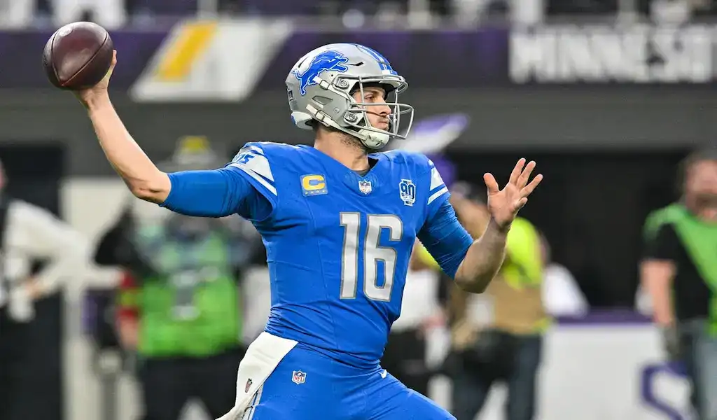 Detroit Lions quarterback preparing to throw a pass during an NFL game against the Minnesota Vikings.