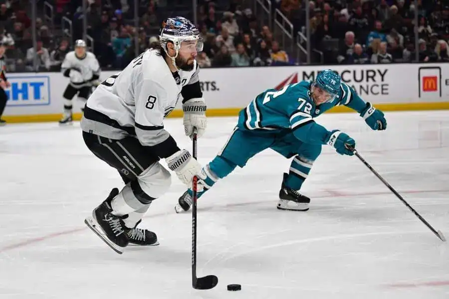 Kings player skates with the puck as a Sharks player attempts to defend.