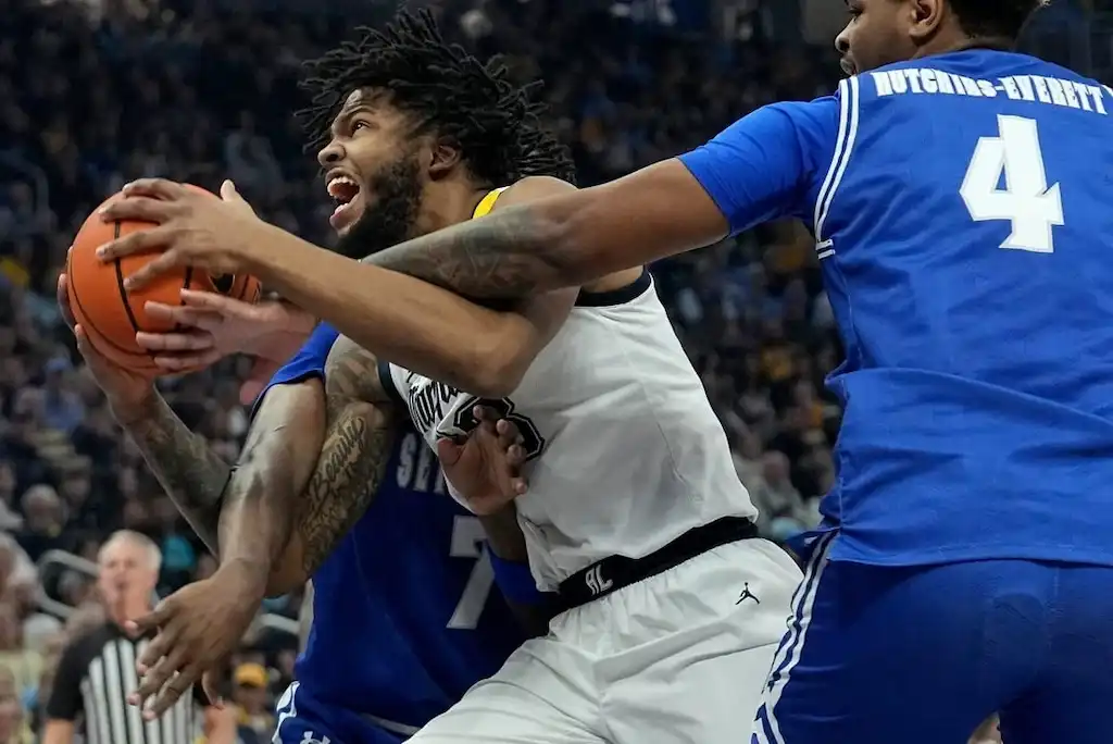 Marquette Golden Eagles player drives to the basket while being defended by two players.