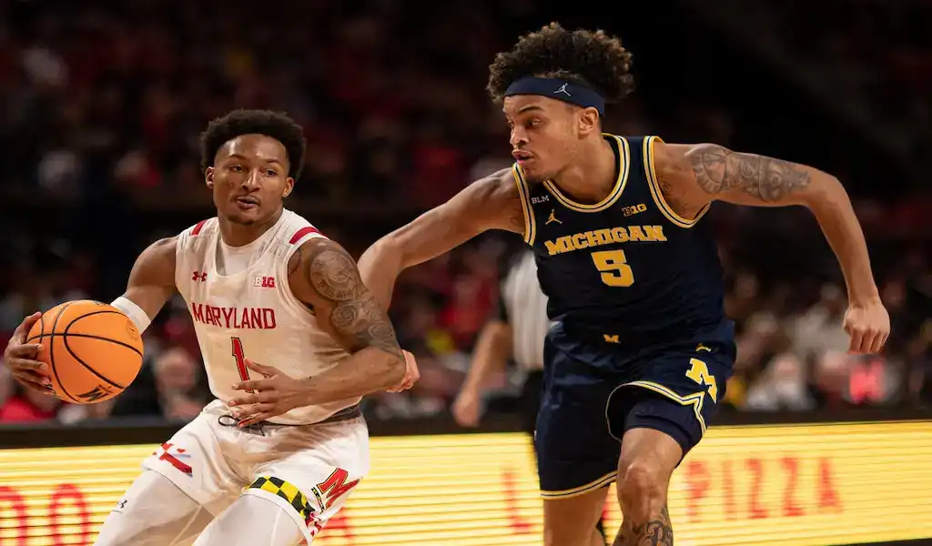 Maryland Terrapins player drives to the basket while being defended by a Michigan Wolverines player during a January 11, 2024 NCAA basketball game.