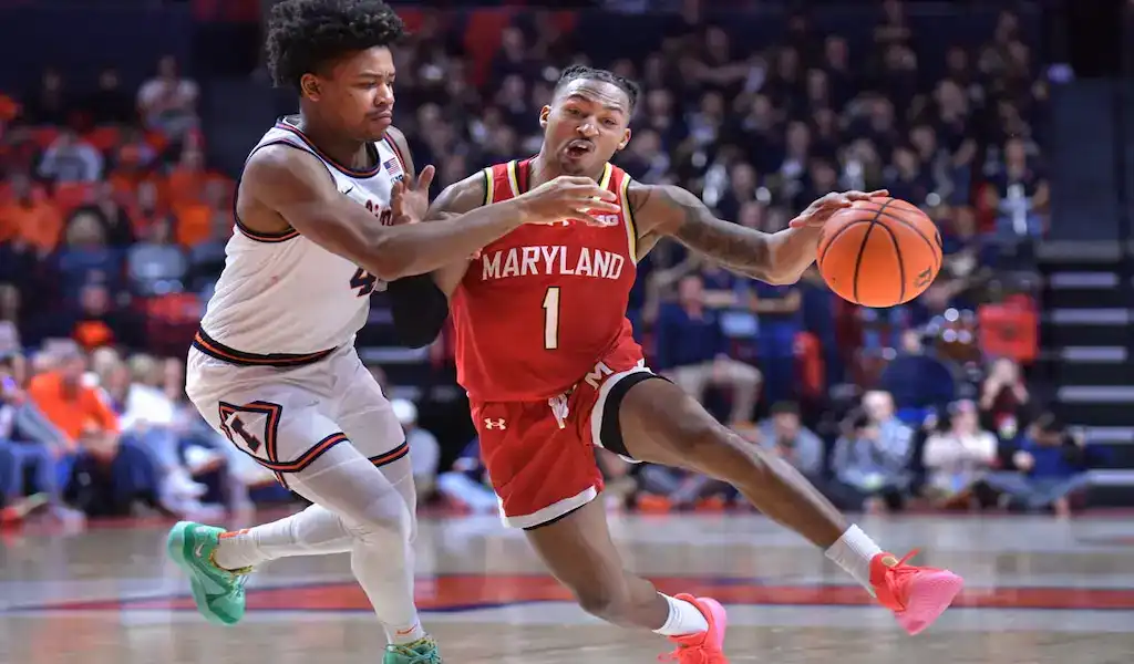 Maryland Terrapins guard drives to the basket while being defended by a Michigan State player during a college basketball game.