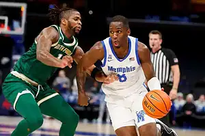 Memphis Tigers basketball player dribbling past a South Florida defender during a college basketball game.