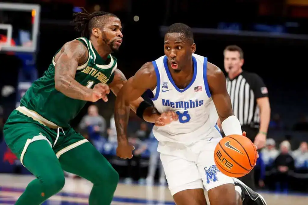 Memphis Tigers basketball player dribbling past a South Florida defender during a college basketball game.
