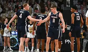 Virginia Cavaliers players high-five during a timeout in NCAA basketball game against NC State Wolfpack.