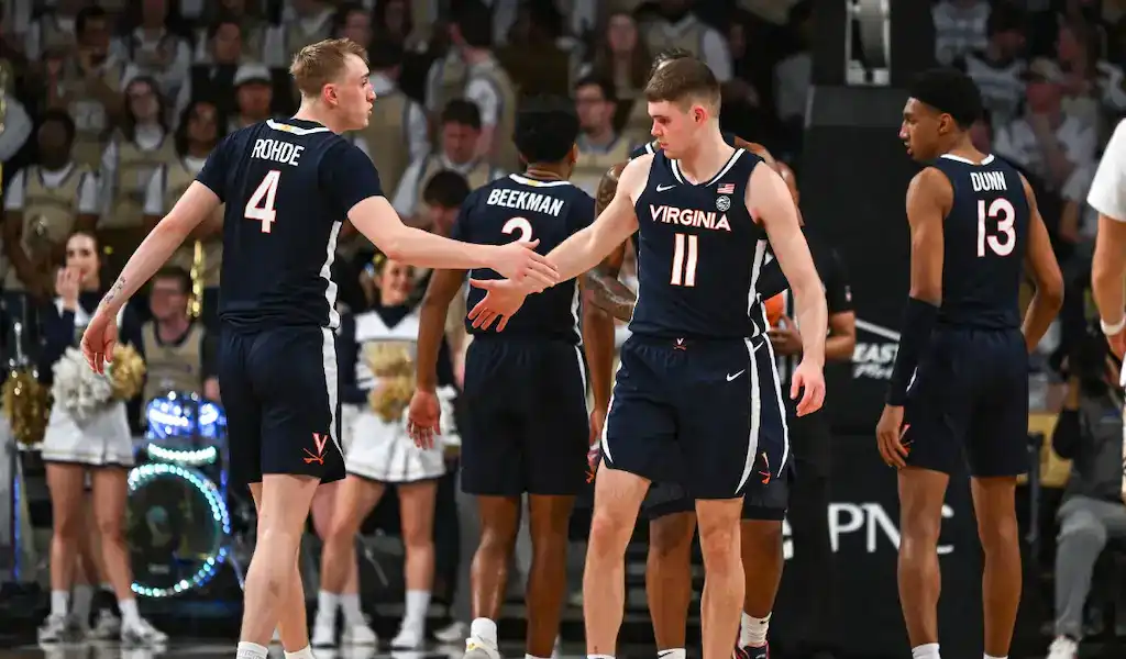 Virginia Cavaliers players high-five during a timeout in NCAA basketball game against NC State Wolfpack.