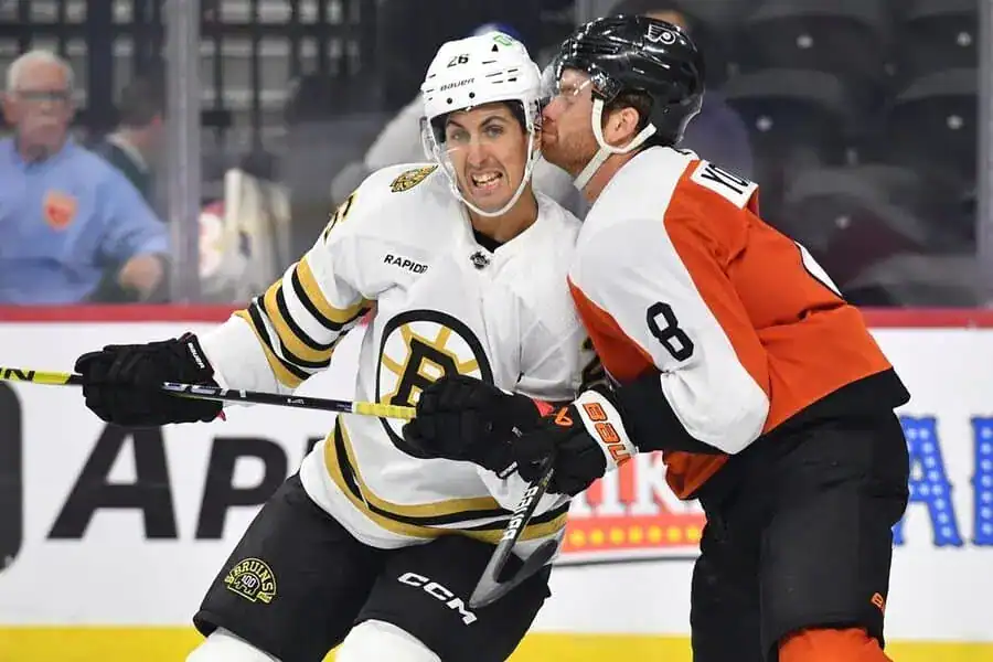 Two hockey players are engaged in a fight while an audience watches in the background.