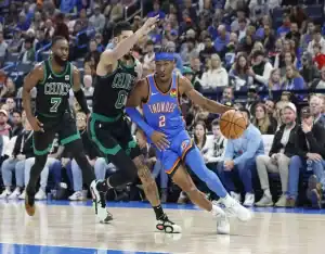 Oklahoma City Thunder guard drives past Boston Celtics defenders during fast-paced NBA game