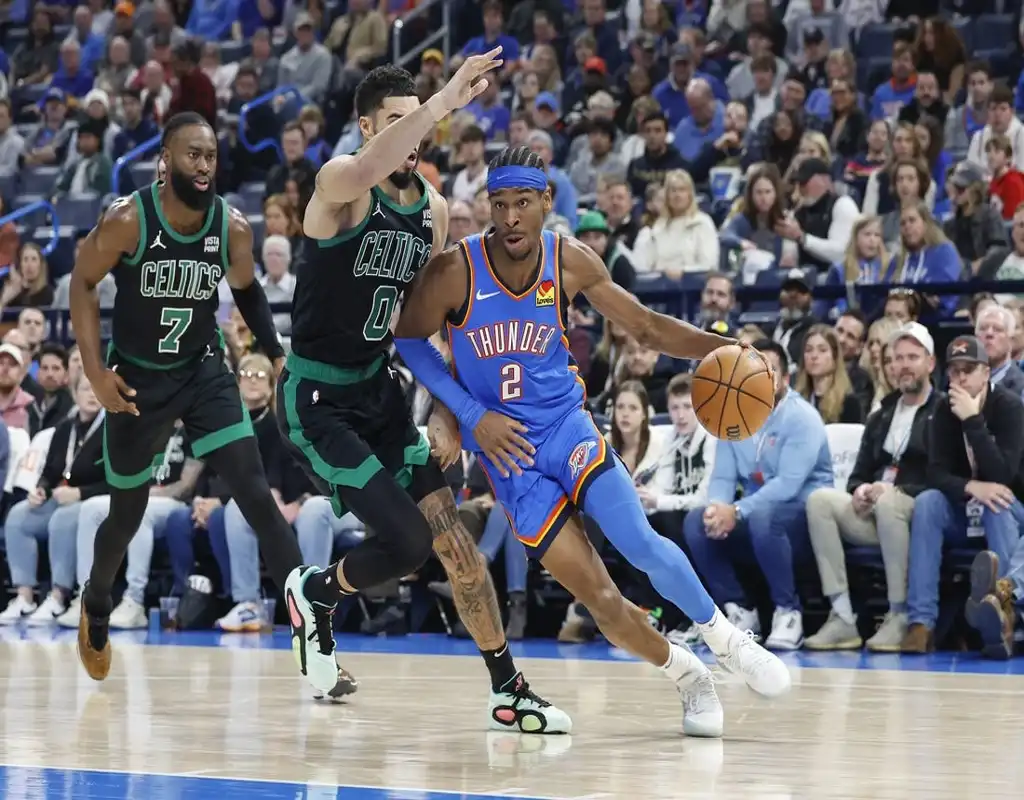 Oklahoma City Thunder guard drives past Boston Celtics defenders during fast-paced NBA game