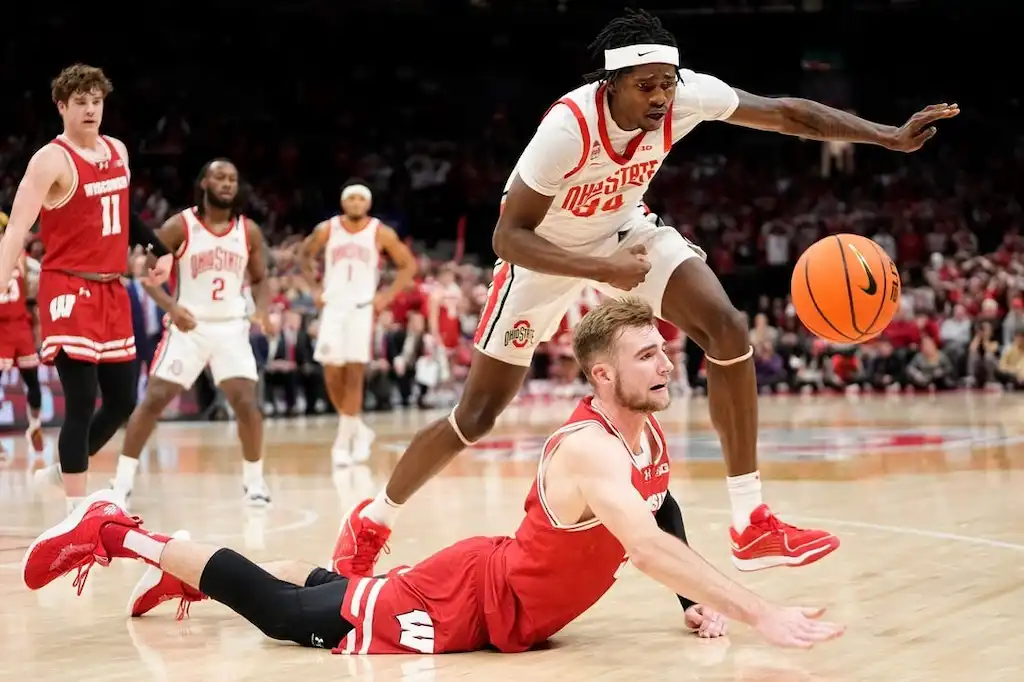 NCAAB 7 An Ohio State player leaps over a Wisconsin player diving for a loose ball.