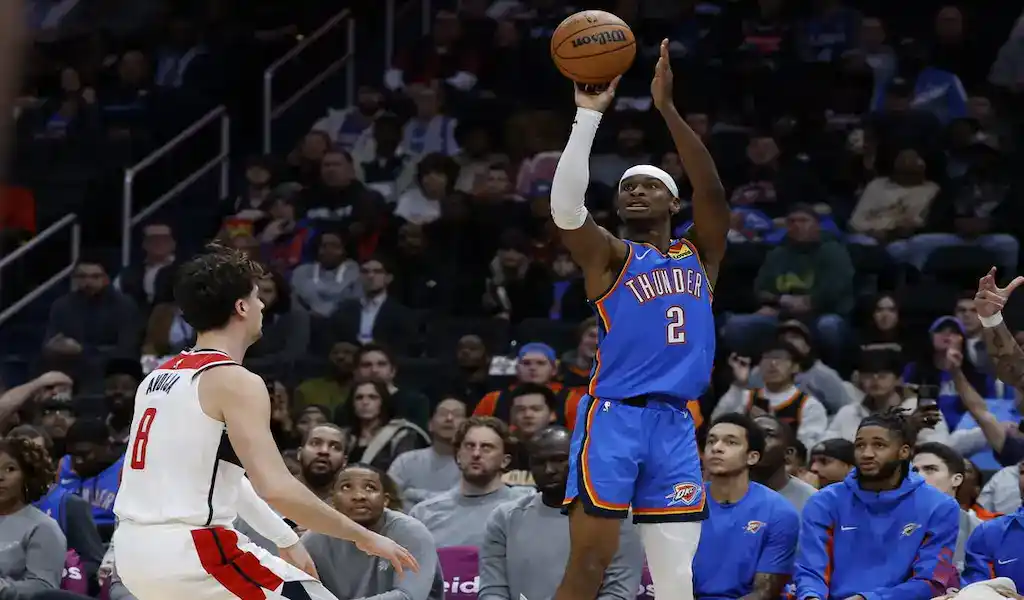 A basketball action shot showing Oklahoma City Thunder player making a shot against the Portland Trail Blazers during a game. The image captures an intense moment in an NBA game between two Western Conference teams.