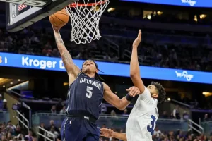 An Orlando Magic player soars toward the basket for a powerful one-handed dunk.