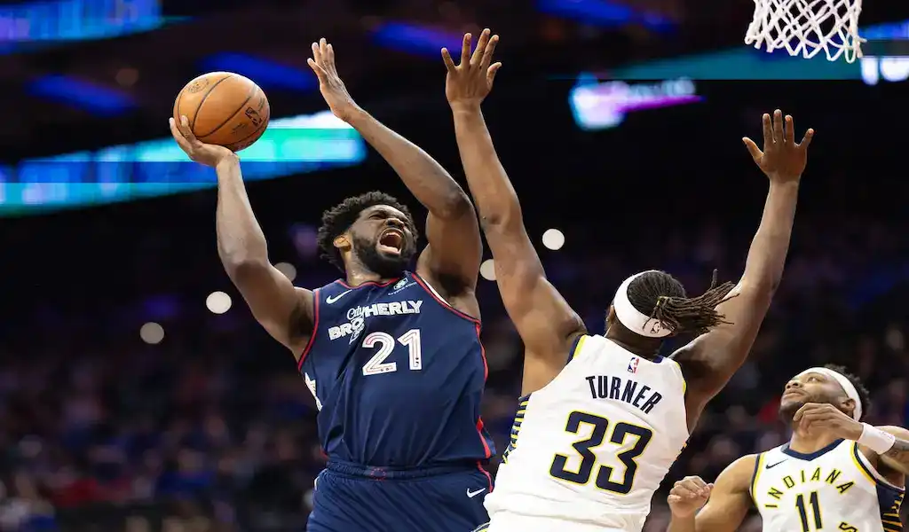 Philadelphia 76ers center driving to the basket against Indiana Pacers defender during an NBA game.
