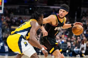 Phoenix Suns player dribbles the ball while being closely guarded by an Indiana Pacers defender.