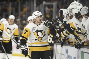 A Pittsburgh Penguins player fist bumps teammates on the bench after a play.
