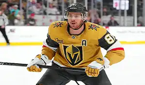 Vegas Golden Knights player in gold jersey skates on the ice during NHL action against the Detroit Red Wings.