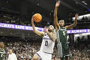 Northwestern player drives for a layup as a Michigan State defender contests the shot.