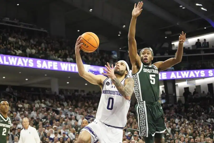 Northwestern player drives for a layup as a Michigan State defender contests the shot.
