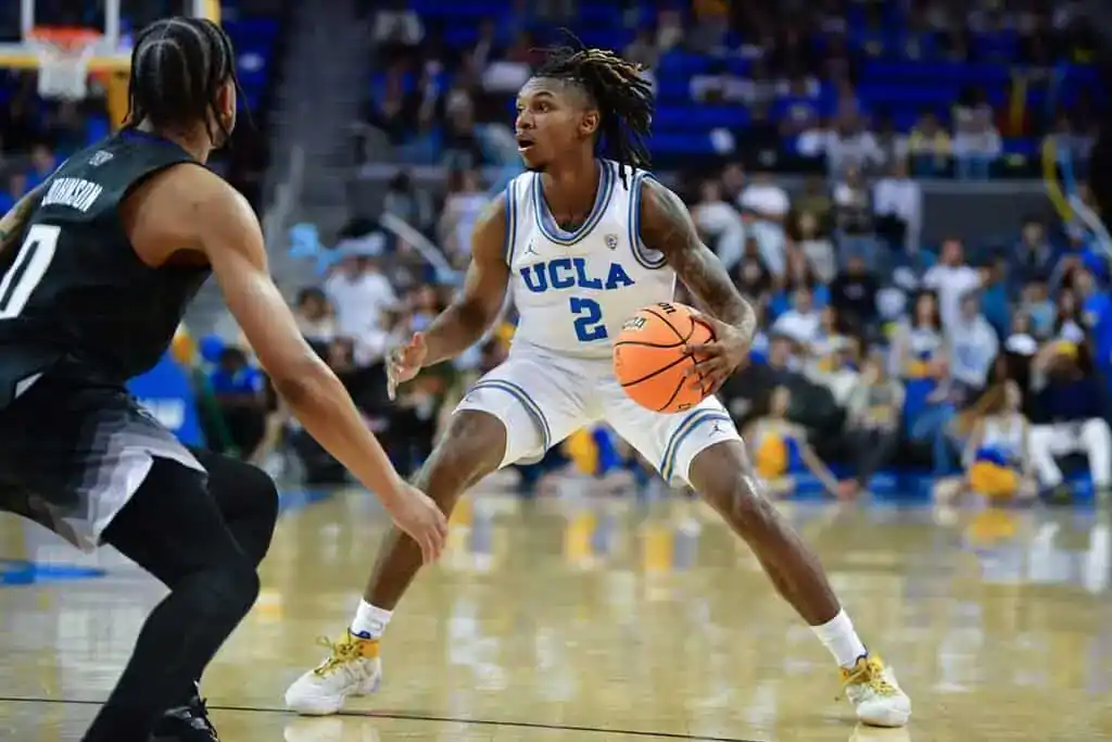 NCAAB 9 UCLA guard dribbles the basketball while facing a defender in a college game.