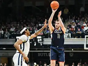 UConn Huskies player rises up for a jump shot over a Butler defender during a college basketball game.