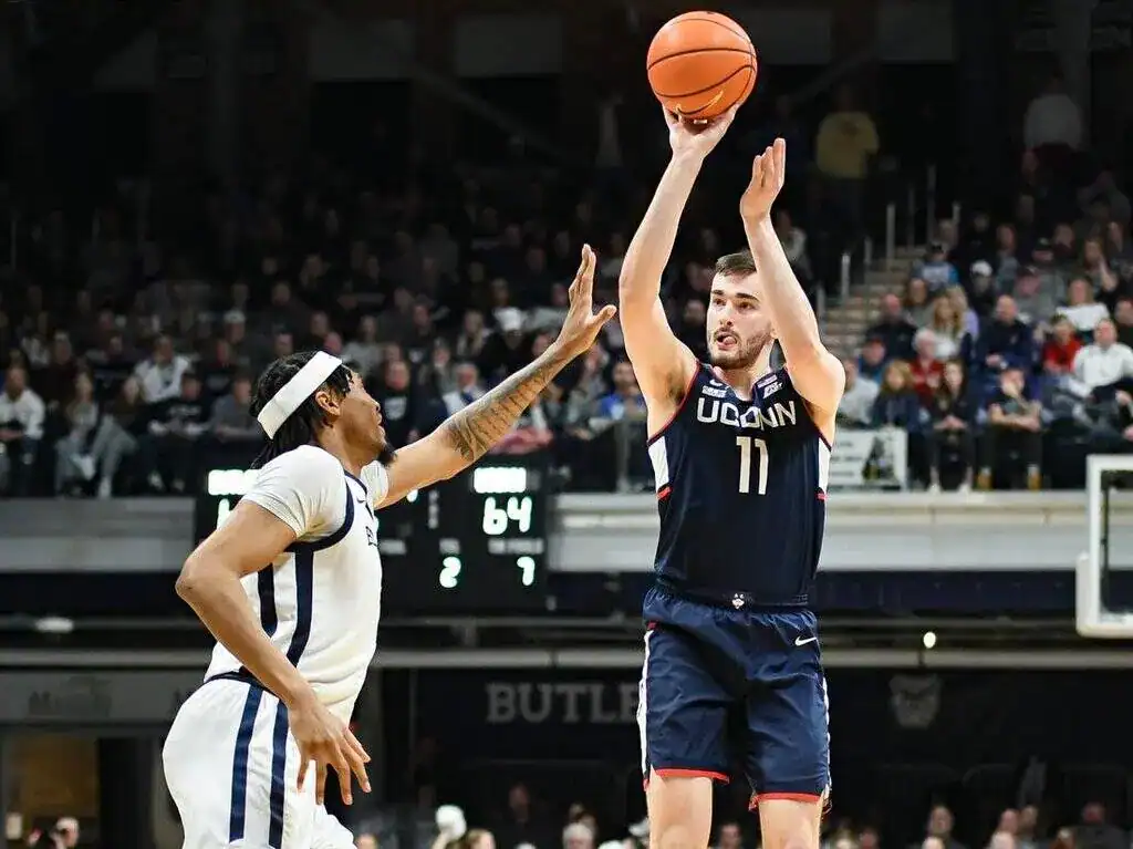 UConn Huskies player rises up for a jump shot over a Butler defender during a college basketball game.