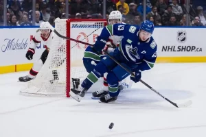 A Vancouver Canucks player maneuvers the puck behind the net.