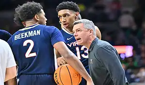 Virginia Cavaliers coach talks with players during a timeout in NCAA basketball game against Virginia Tech Hokies.