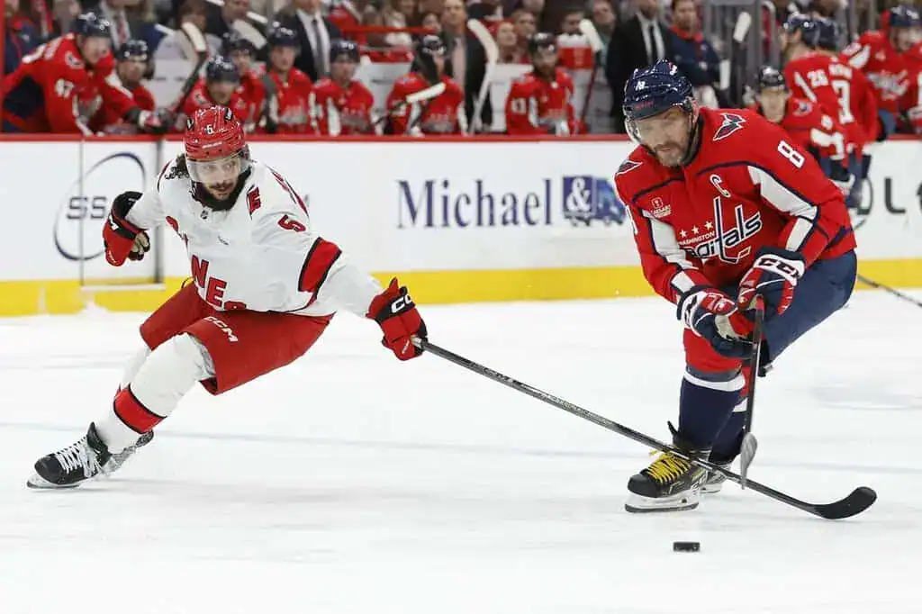 Washington Capitals forward skates with the puck while defended by a Carolina Hurricanes player.