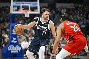 Dallas Mavericks player Luka Dončić dribbles while being defended by a Toronto Raptors player during an NBA game.