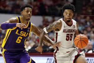 An Alabama basketball player dribbles the ball upcourt while being closely defended by an LSU player.
