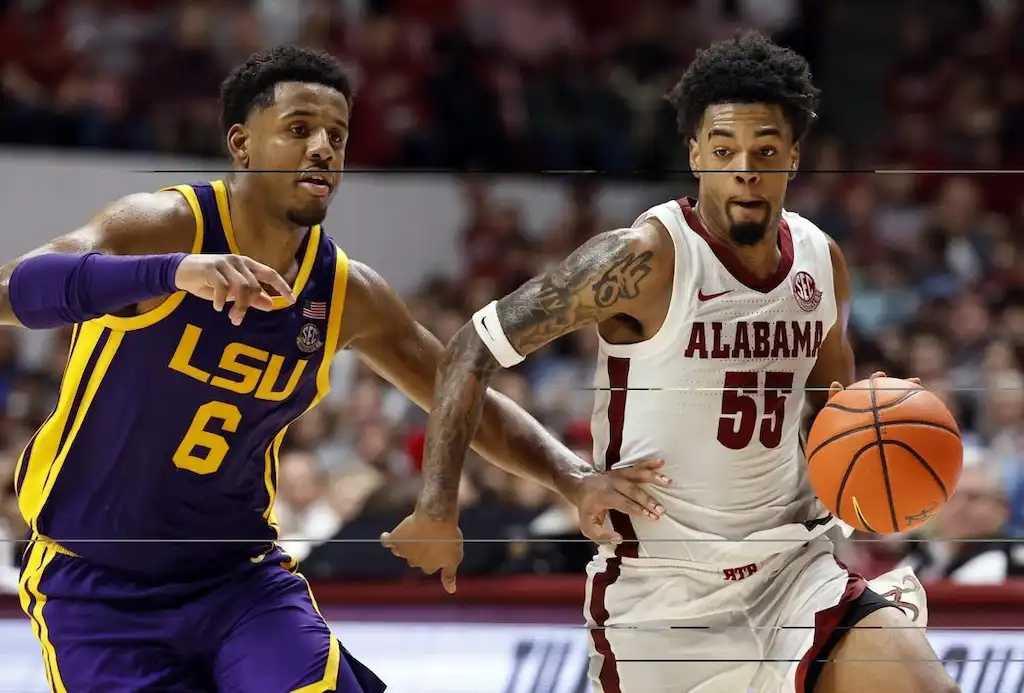 An Alabama basketball player dribbles the ball upcourt while being closely defended by an LSU player.