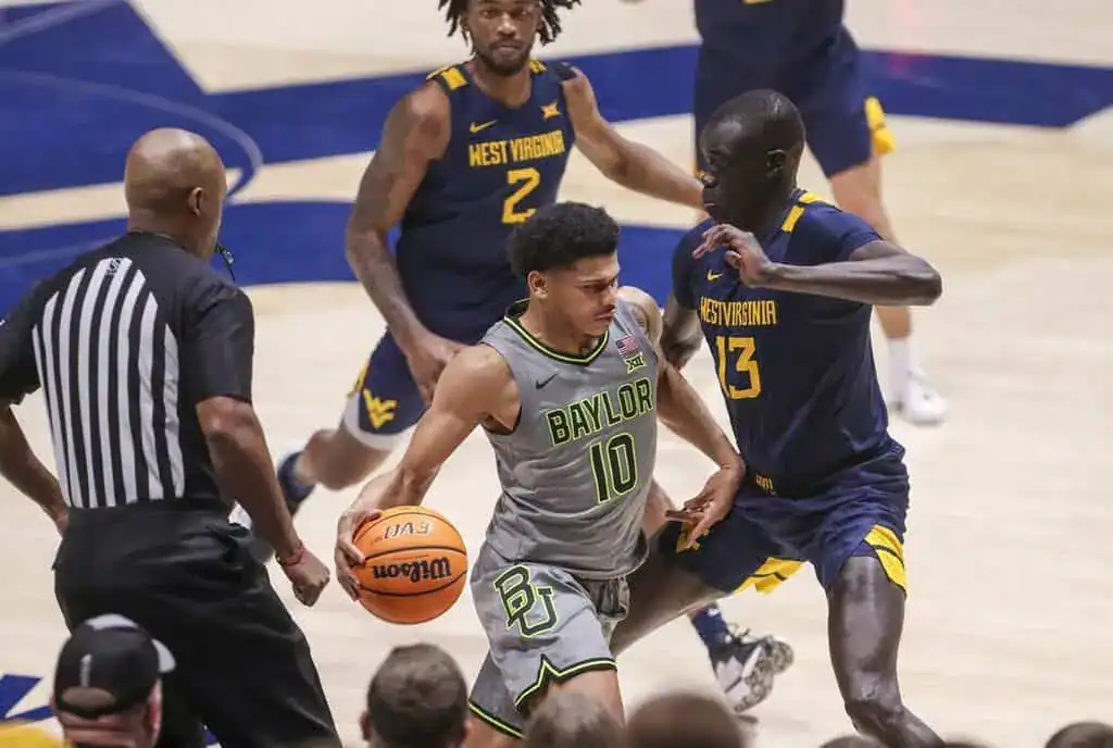 Baylor guard dribbles aggressively while being tightly defended by a West Virginia player during a college basketball game