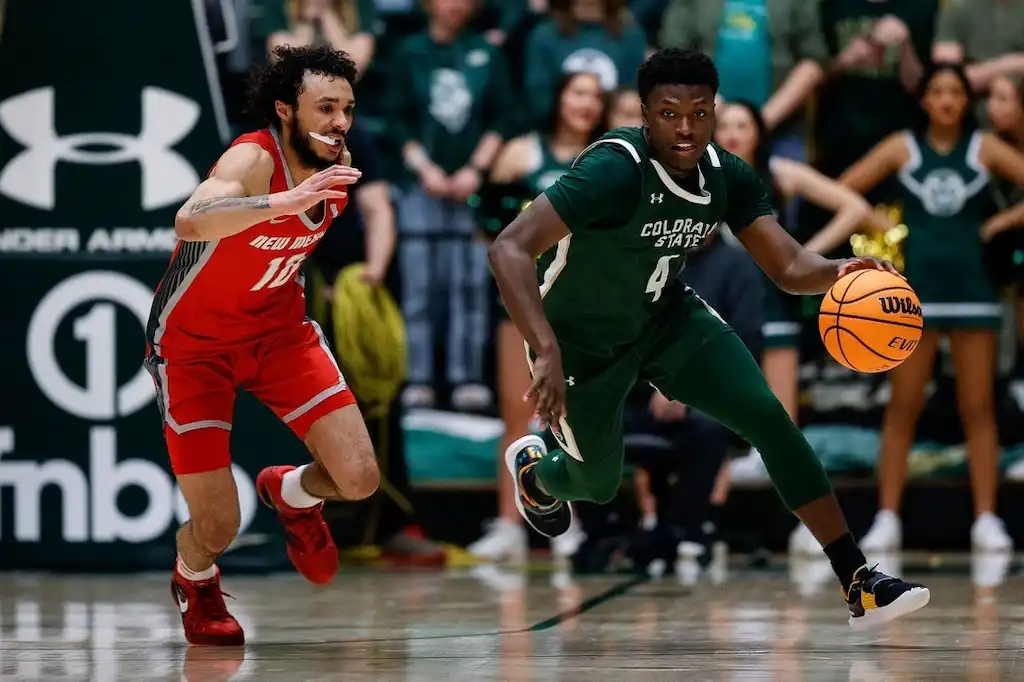A Colorado State basketball player drives the ball up the court.