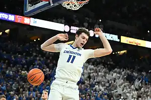 A Creighton player wearing number 11 reacts after a slam dunk during a college basketball game.