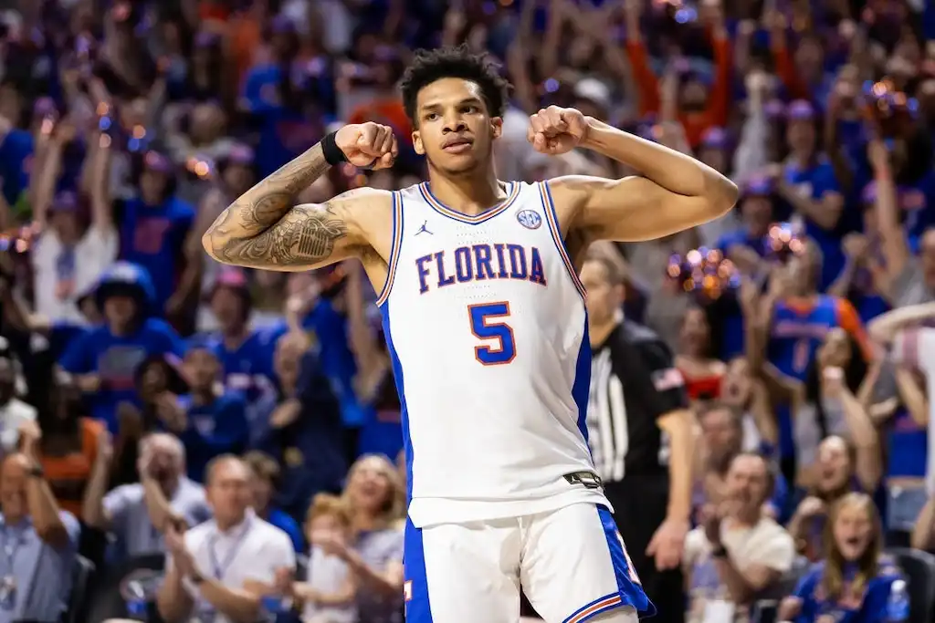 A Florida Gators basketball player flexes his arms and celebrates .