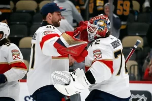 Two Florida Panthers players celebrate on the ice after a victory.