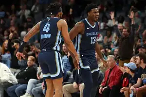 Two basketball players are joyfully celebrating together on the court after a successful play.