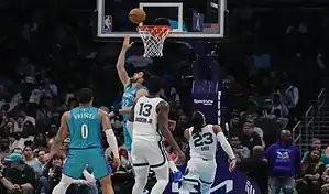 Charlotte Hornets player attempts a layup against Indiana Pacers defenders during an NBA game.