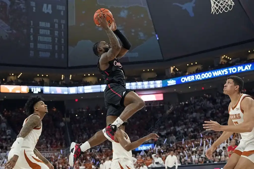 A Houston Cougars basketball player soars through the air for a layup or dunk.