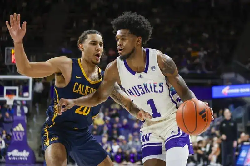 NCAAB 5 Washington Huskies basketball player dribbles past a California Golden Bears defender in a college basketball matchup.