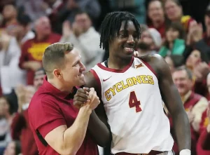 An Iowa State player shares a celebratory handshake and smile with a coach.