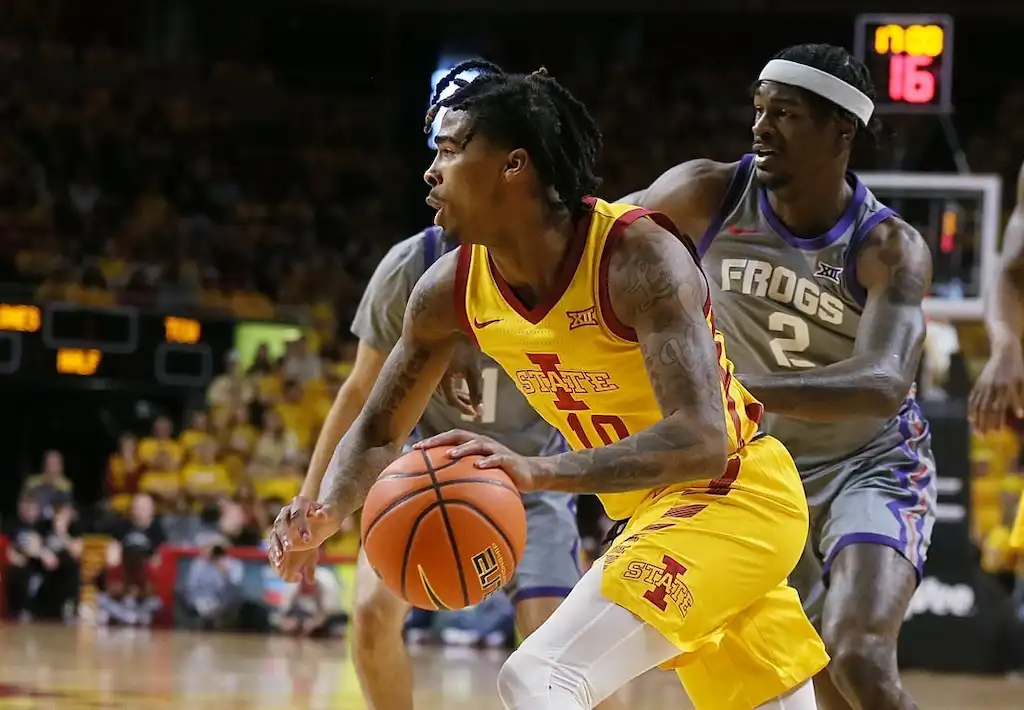 NCAAB 5 Iowa State basketball player drives toward the basket while being closely defended by a TCU player.