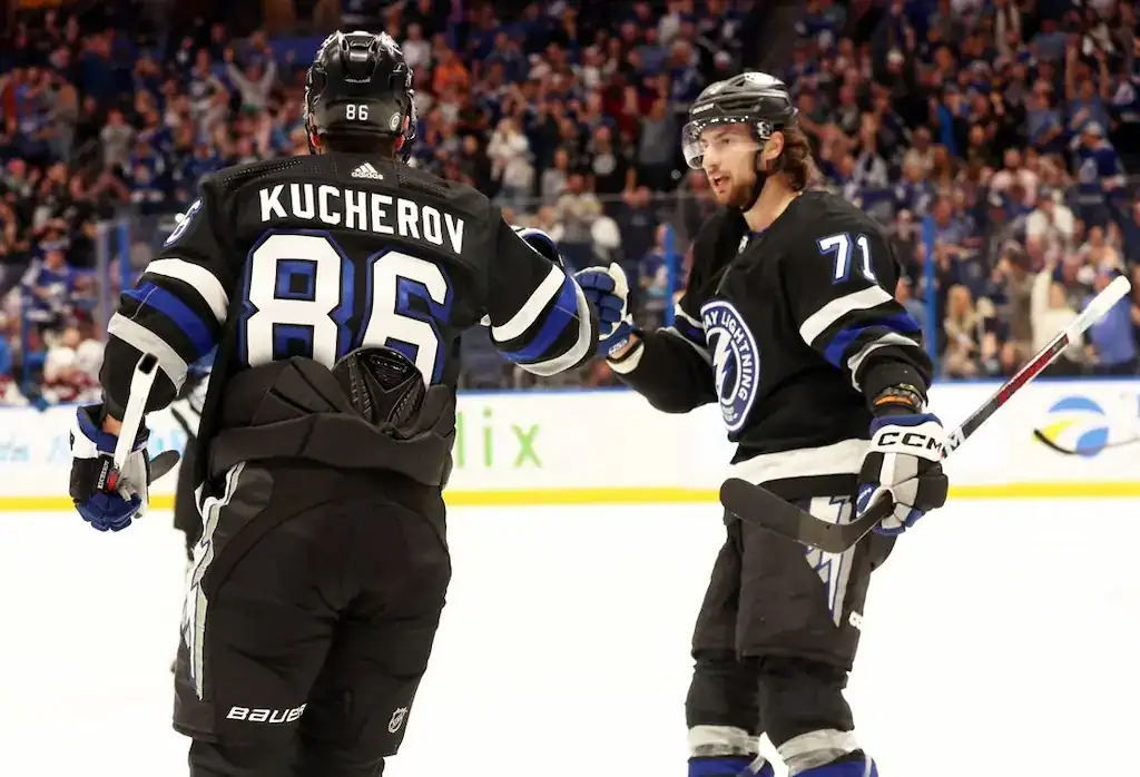 Tampa Bay Lightning players Nikita Kucherov and Anthony Cirelli celebrate on the ice in black uniforms.
