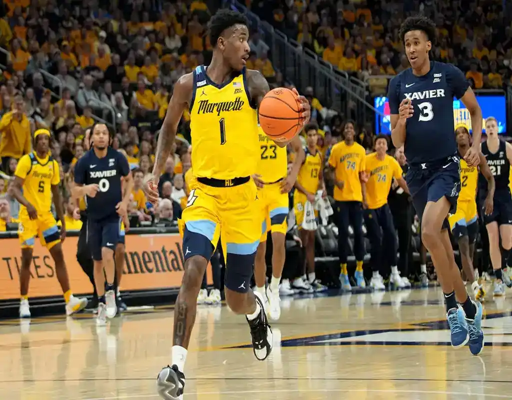 Marquette Golden Eagles player leads fast break while being chased by Xavier defenders during college basketball game