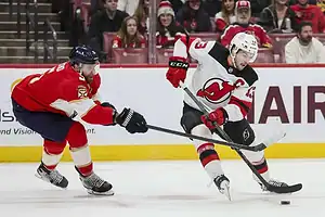 New Jersey Devils player skates with puck against Panthers.