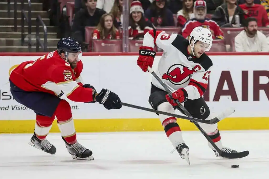 New Jersey Devils player skates with puck against Panthers.