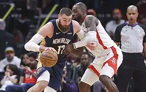 New Orleans Pelicans player drives aggressively with the ball while being defended by a Houston Rockets player